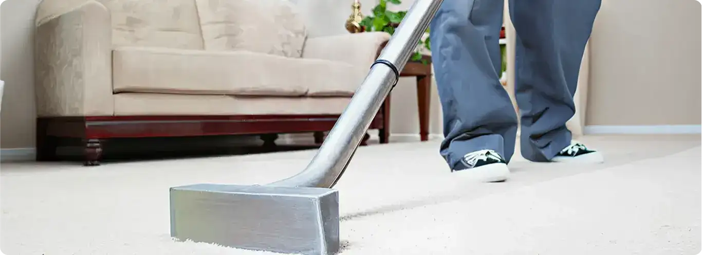 Carpet cleaning technician using a hot-water extraction wand on a light-colored carpet in a living room, Tulsa, OK.